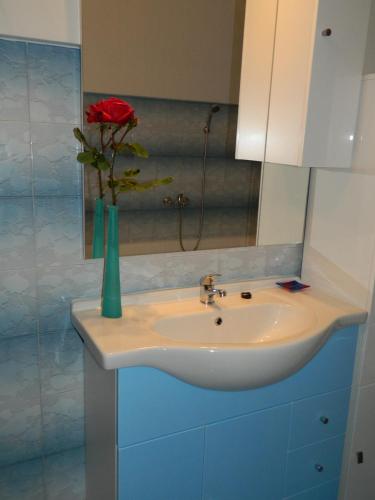 a bathroom with a sink with a rose in a vase at Bartulovi dvori in Poljica