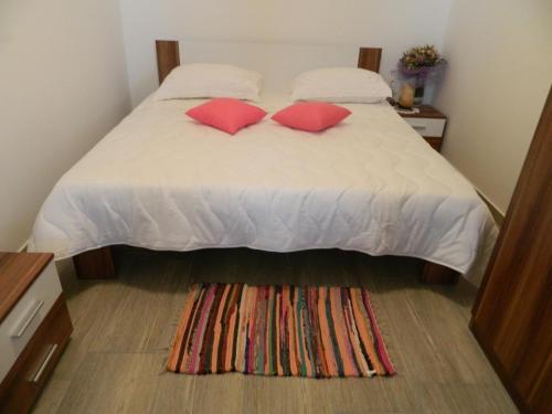 a bedroom with a bed with two pillows and a rug at Bartulovi dvori in Poljica