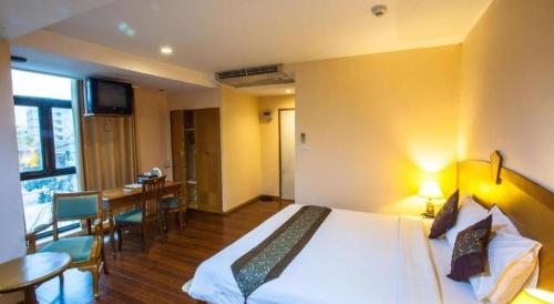 a hotel room with a bed and a dining room at NH Elegant Hotel in Sakon Nakhon