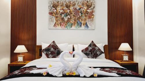 two white swans are sitting on a bed at Asna House in Ubud