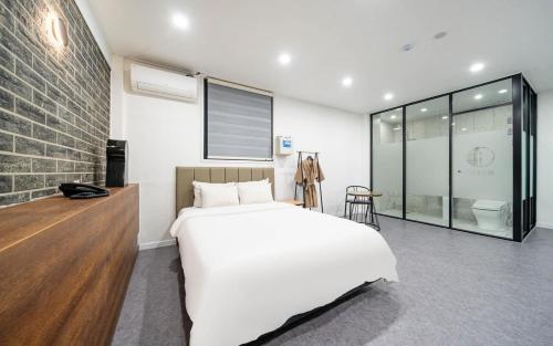a bedroom with a white bed and a brick wall at Traum Hotel in Goyang