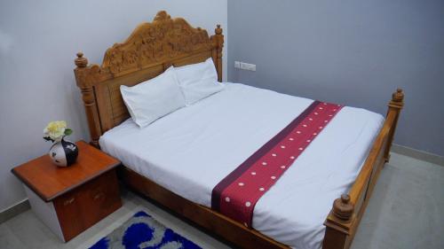 - une chambre avec un lit doté d'une tête de lit en bois et d'une table dans l'établissement Dazicor Retreats - Luxury Villa in Kottarakara, 