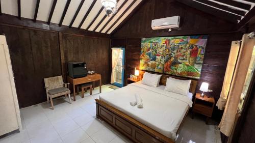 a bedroom with a bed and a painting on the wall at Tahlia's Villa in Sorongjukung