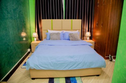 a bedroom with a large bed with blue sheets and pillows at Blaize Affaire apartments in Kampala
