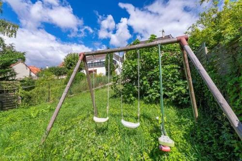 an empty swing set in a field of grass at Grande maison familiale avec suite parentale Proche Paris aéroport CDG et Parc Astérix in Fosses