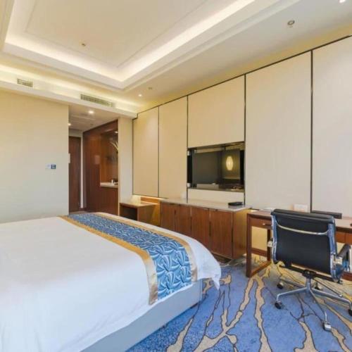 a bedroom with a bed and a desk and a tv at YUN-RAY Hotel Shijiazhuang in Shijiazhuang