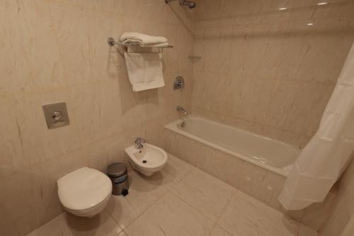 a bathroom with a toilet and a tub and a sink at Monteverde Hotel in Beit Meri