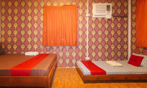 a room with two beds and a wall with orange curtains at RedDoorz @ Boondocks Cabins Resort in Dalumpinas Oeste