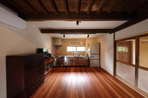 a kitchen with wooden floors and a kitchen with a refrigerator at 古民家一棟貸別荘 しずく亭 -Kominka SHIZUKU tei- in Mobara