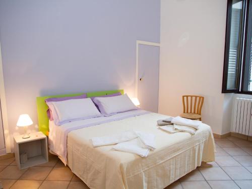 een slaapkamer met een bed met witte lakens en een stoel bij B&B Corte dell' Idume in Lecce