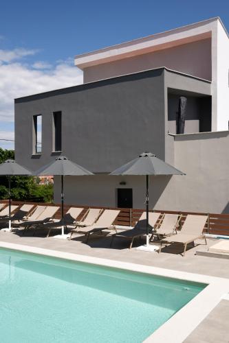 a group of chairs and umbrellas next to a pool at Kyan Executive Suites in Iraklitsa