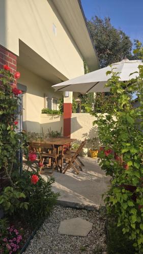 une terrasse avec une table en bois et un parasol dans l'établissement Maison au calme avec jardin clos, à Berck-sur-Mer