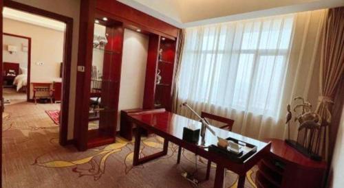 a living room with a desk and a large window at Qingdao Blue Horizon Hotel Licang in Qingdao