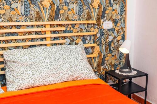 una camera da letto con un letto arancione con una parete floreale di Holiday Home Ettore a Catania