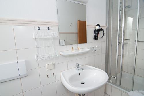 a white bathroom with a sink and a shower at Vitalhotel Weisse Elster in Bad Elster
