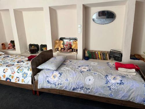 a bedroom with two beds and a clock on the wall at ХОСТЕЛ ТаСмИн МеХр РеГиСтАн in Samarkand