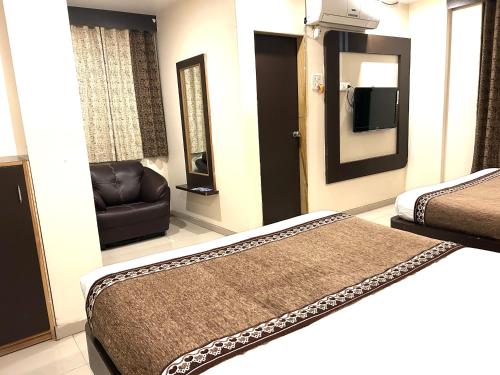 a hotel room with two beds and a chair at Hotel Krishna Sai Kutir in Shirdi