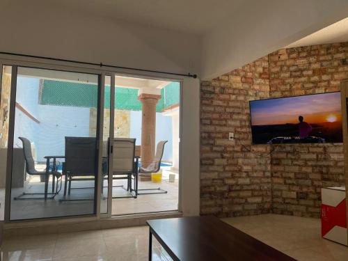 a living room with a television on a brick wall at Casa Chuy pueblo mágico in Xochitepec