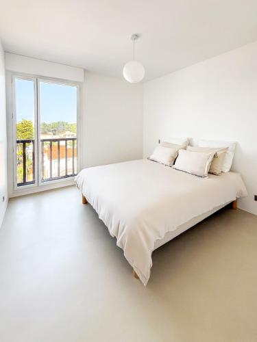 une chambre blanche avec un grand lit et une fenêtre dans l'établissement Front de mer, confort et élégant, à Saint-Jean-de-Monts
