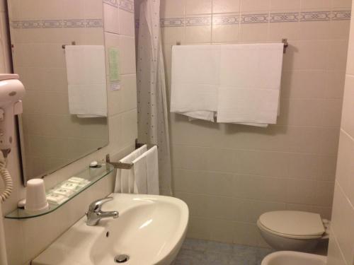 uma casa de banho com lavatório, WC e toalhas em Hotel Strand em Marina di Montenero