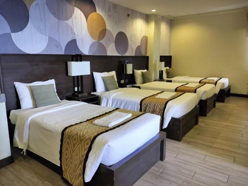 a group of four beds in a hotel room at Whitewoods Convention and Leisure Hotel by SMS Hospitality in Silang