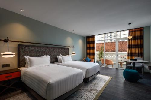 a hotel room with two beds and a table and a desk at The George Penang by The Crest Collection in George Town