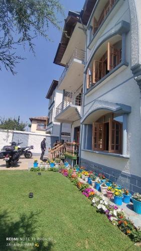 a blue building with flowers in a yard at Moonshine Homestay Kashmir in Srinagar