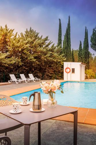 a table with a tea kettle and flowers next to a pool at Apiedesierra - Caserio del Colmenar in Huétor Santillán