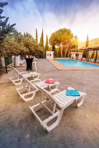 a row of white lounge chairs next to a swimming pool at Apiedesierra - Caserio del Colmenar in Huétor Santillán