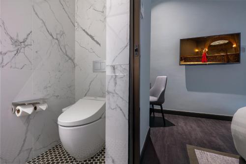 a bathroom with a toilet and a tv on the wall at The George Penang by The Crest Collection in George Town