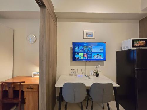 a dining room table with two chairs and a tv on the wall at 1BR Condotel with Balcony at FAME Residences #FM58-1 in Manila