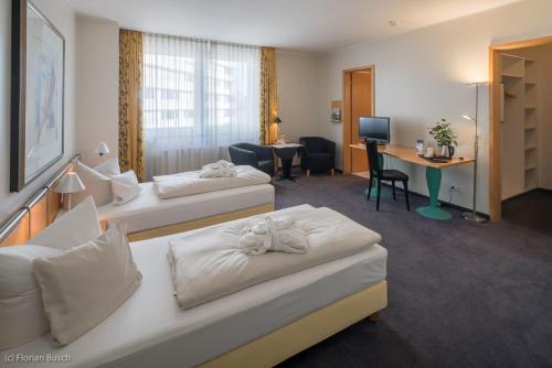 a hotel room with two beds and a desk at Best Western Hotel im Forum Mülheim in Mülheim an der Ruhr