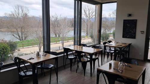 un restaurant avec des tables et des chaises et de grandes fenêtres dans l'établissement Le Préau de Baix, à Baix