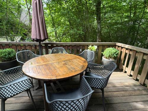 a wooden table and chairs on a deck with an umbrella at Chalet Séquoia 138 Nature, piscine et chien bienvenu à Durbuy in Durbuy