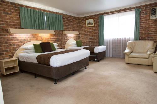 a hotel room with two beds and a chair at A Line Motel in Griffith