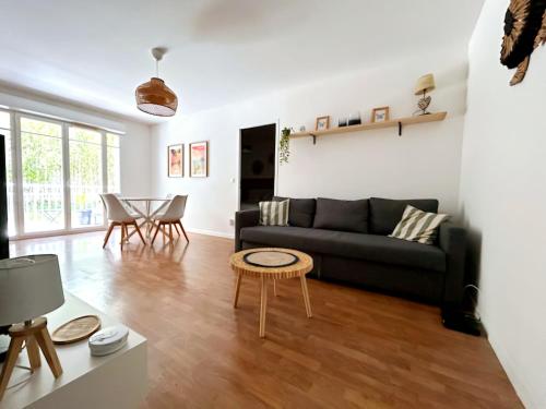 un salon avec un canapé noir et une table dans l'établissement Le cosy bisca-Parking-terasse-Lac-Océan, à Biscarrosse