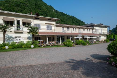 a large white building with a courtyard with tables and chairs at La Sosta Hotel in Vestone