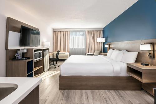 a hotel room with a large bed and a sink at Comfort Suites Kingston Central in Kingston