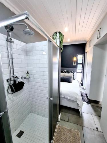 a bathroom with a shower and a bed in a room at Tiny Home on Broadway in Gqeberha