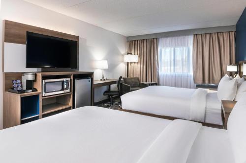 a hotel room with two beds and a flat screen tv at Comfort Suites Kingston Central in Kingston