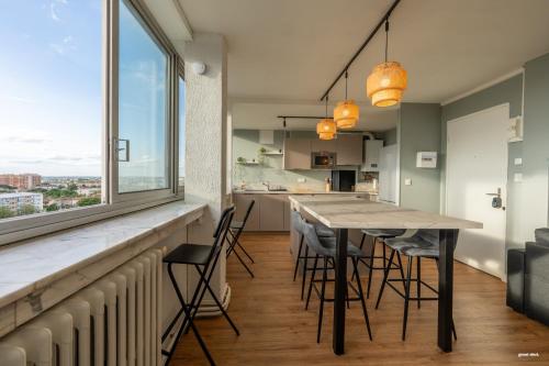 une cuisine avec une table et des chaises ainsi qu'une grande fenêtre dans l'établissement Toulouse Appartment 3 bedrooms balcony panoramic view - 10 min Train station & Metro, à Toulouse