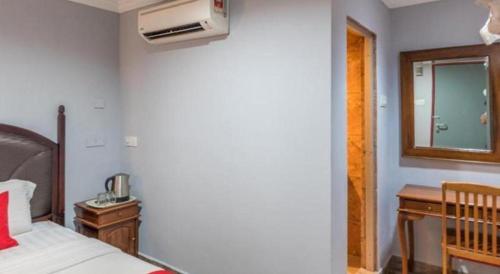 a bedroom with a bed and a desk and a window at OYO 890 Hotel RK Cahaya in Labuan