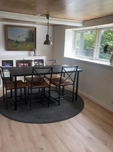 a dining room with a black table and chairs at Charmerende sommerhus i fredelige omgivelser in Skorping