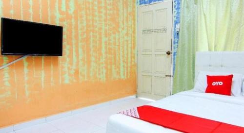 a bedroom with a bed and a tv on a wall at OYO 89684 Mawaddah Inn Stay in Tangkak