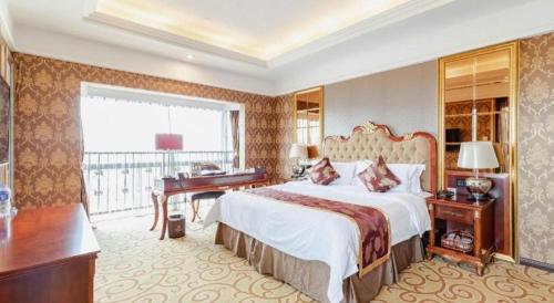 a hotel room with a large bed and a desk at Royal Duke Cherrabah Hotel Zhongshan in Yagang