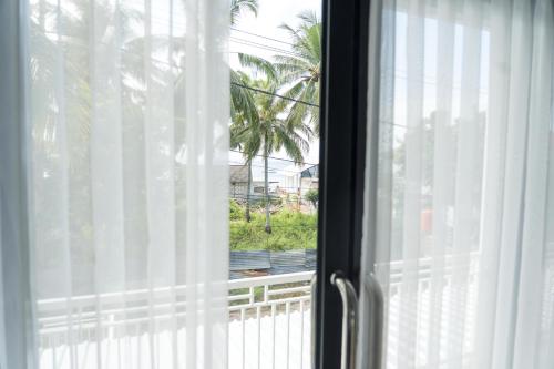 a window with a view of a palm tree at The Joy Culinary & Room in Toyapakeh