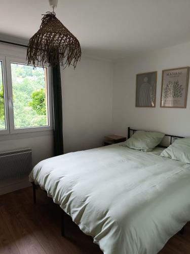 une chambre avec un grand lit blanc avec une fenêtre dans l'établissement Bas de Villa avec entrée indépendante en pleine nature, à Le Bar-sur-Loup