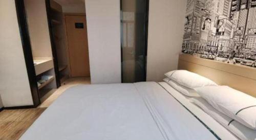a white bed in a room with a picture on the wall at City Comfort Inn Ji'an South Administrative Center in Ji'an