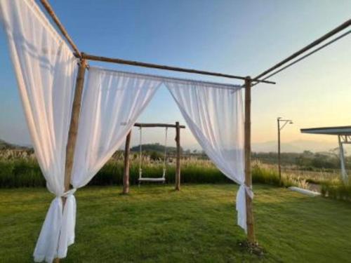 a marquee with a white curtain in a field at Nordic Hills Kanchanaburi in Ban Chek