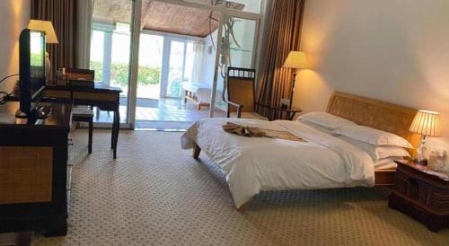 a bedroom with a bed and a desk and a piano at Kunming Dianchi Garden Hotel & Spa in Kunming